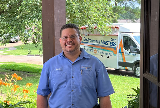 An Environment Masters plumber smiling with an Environment Masters truck parked in the background.