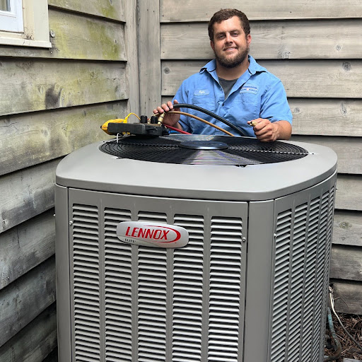 An Environment Masters technician standing in front of a Lennox heat pump unit.