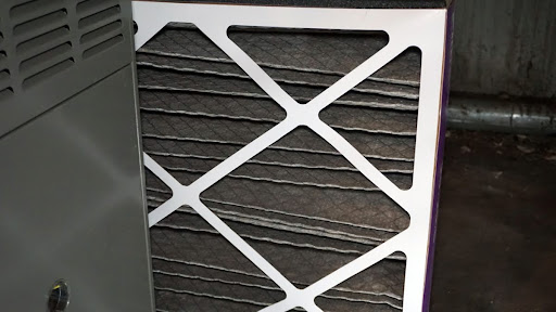 An air filter positioned next to a furnace.