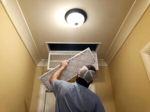 A man replacing an HVAC air filter.