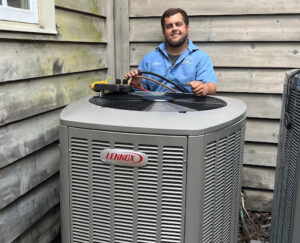 A smiling Environment Masters technician standing near a heat pump unit outdoors.